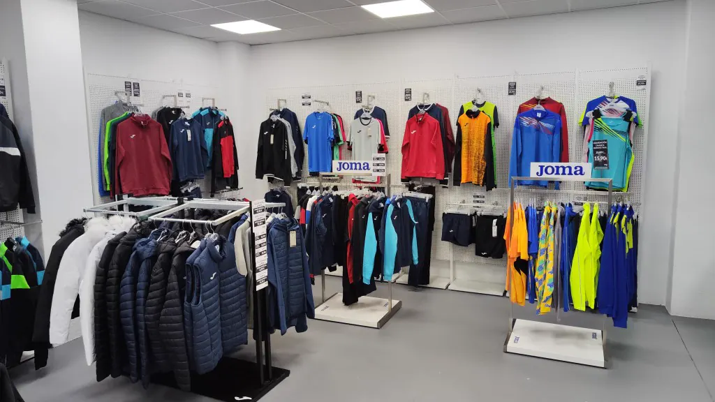Exposición de equipaciones y chaquetas Joma en la tienda física de Granada